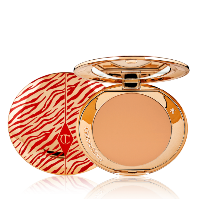 An open, pressed powder compact for tan skin tones with a mirrored lid, in gold-coloured packaging with red-coloured tiger stripes on the lid.