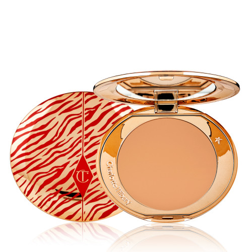 An open, pressed powder compact for tan skin tones with a mirrored lid, in gold-coloured packaging with red-coloured tiger stripes on the lid.