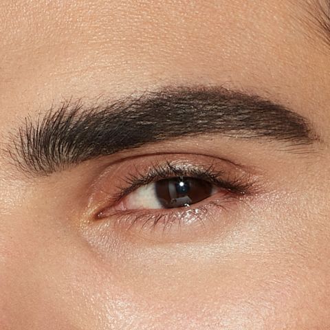 Single-eye close-up of a male model with brown eyes with shaped, lined, and filled-in brows in a black-brown colour that makes the eyebrows look full and lush.