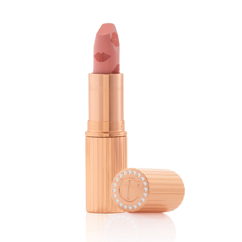 An open lipstick in a muted pink shade in a gold-coloured tube with its lid next to it.