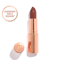 Opened, berry-pink lipstick in a metallic, golden case with its lid that's embossed with CT placed next to it. 