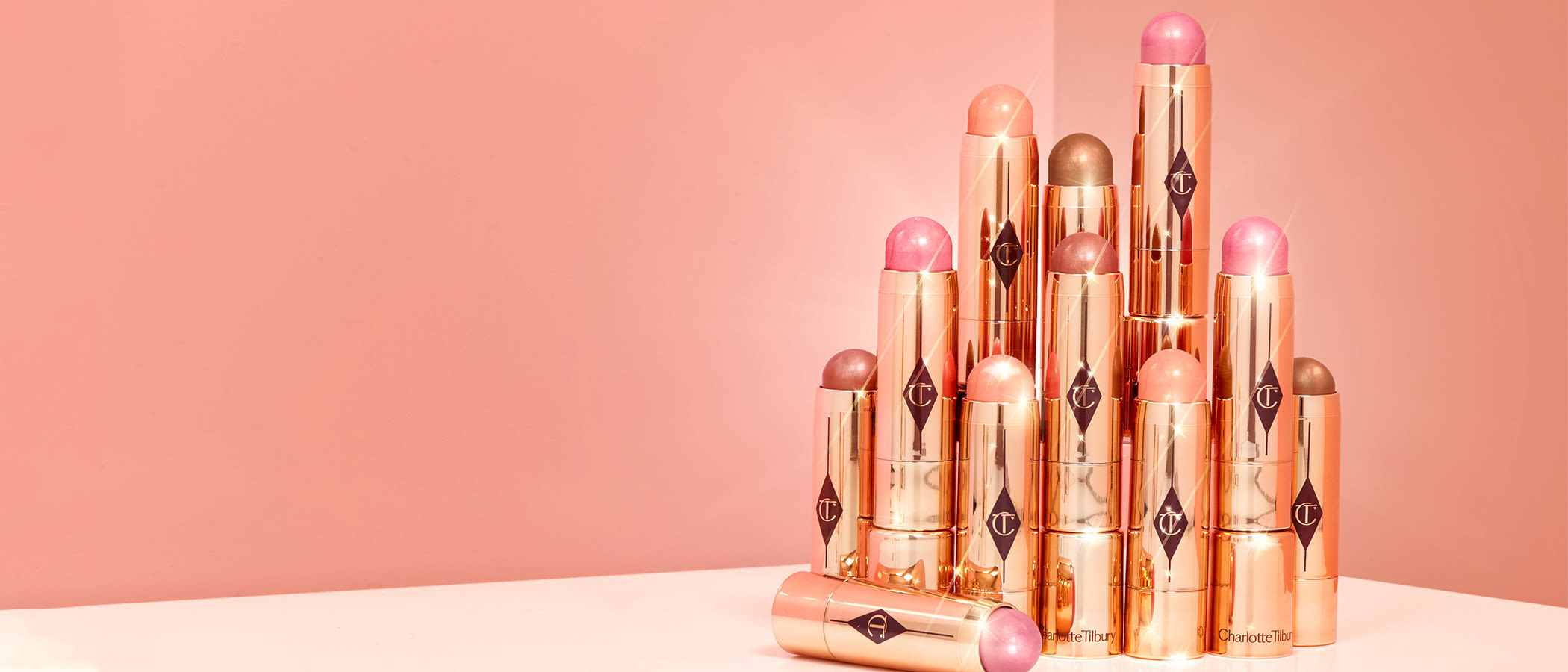 A pile of blush sticks in nude pink, cool pink, coral, berry, and bronze with rose-gold packaging and the CT logo printed on all of them. 