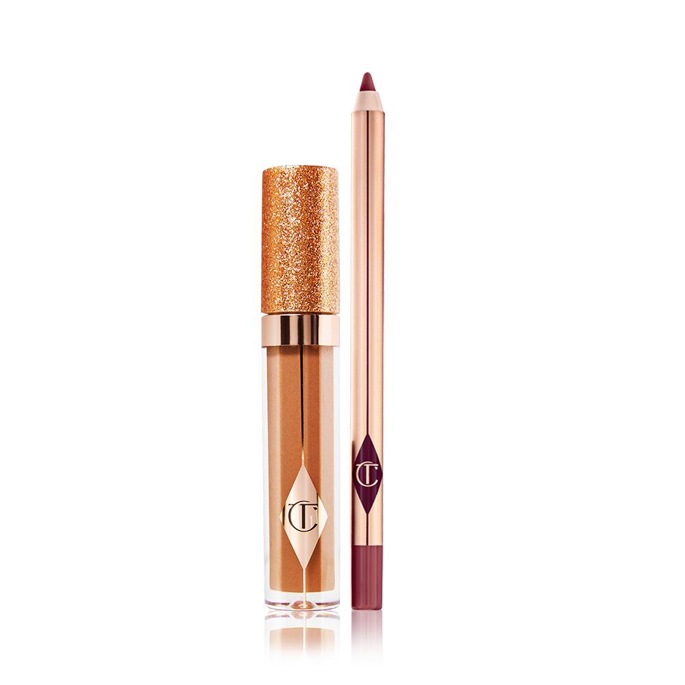 A shimmery Lip gloss in a bronze-gold shade in a glass tube with a glittery lid with a lip liner pencil in a dark winter berry shade.