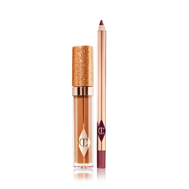 A shimmery Lip gloss in a bronze-gold shade in a glass tube with a glittery lid with a lip liner pencil in a dark winter berry shade.