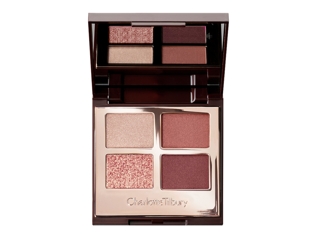 An open, quad eyeshadow palette with a mirrored lid with eyeshadows in shades of russet rose, dark brown, rose gold, and dull gold.