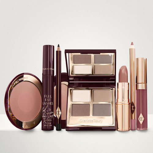 An open, mirrored-lid eyeshadow palette in matte and shimmery taupe, grey, and beige shades, an open black eyeliner pencil, a mascara in a dark-crimson colour scheme, a nude-peach lipstick with a matching lip liner pencil, magenta lip gloss, and an open two-tone blush in muted brown-pink. 