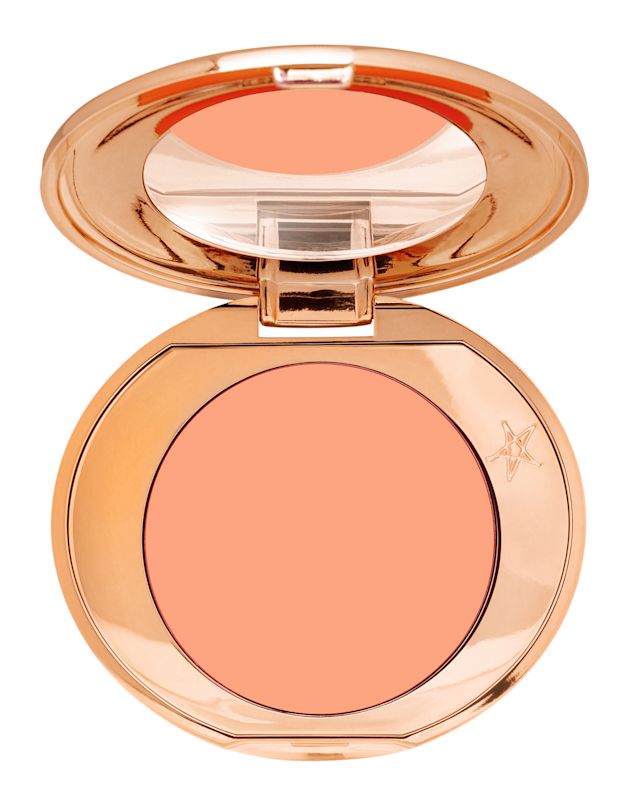 A colour corrector compact in a warm peach shade with a mirrored-lid in golden-coloured packaging. 