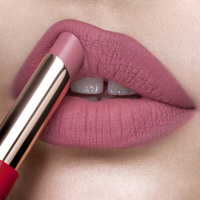 Lips close-up of a fair-tone model applying a lipstick in a neutral rosy-pink colour with a matte finish.