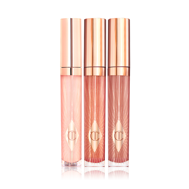 Three lip glosses in shades of light pink, coral-peach, and brown-pink in glass tubes with gold-coloured lids. 