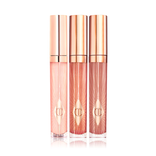 Three lip glosses in shades of light pink, coral-peach, and brown-pink in glass tubes with gold-coloured lids. 