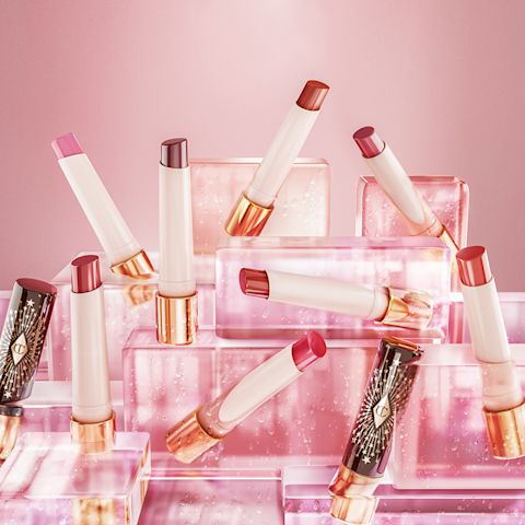 A collection of open, moisturising, high-shine lipstick balms in shades of red, pink, purple, brown, peach, and coral in white and gold-coloured tubes with black-coloured lids with gold-coloured stars printed all over.