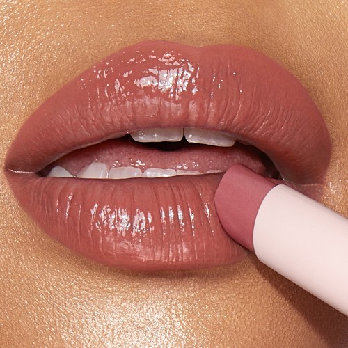 Lips close-up of a light-tone model wearing a moisturising lipstick balm in a nude pink shade.