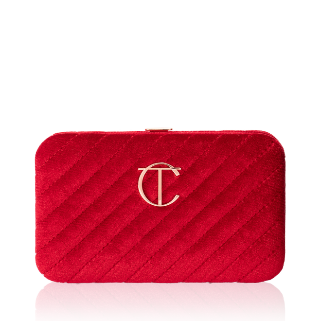 A closed, bright-red-coloured velvet brush clutch with the iconic CT logo on the front in gold.