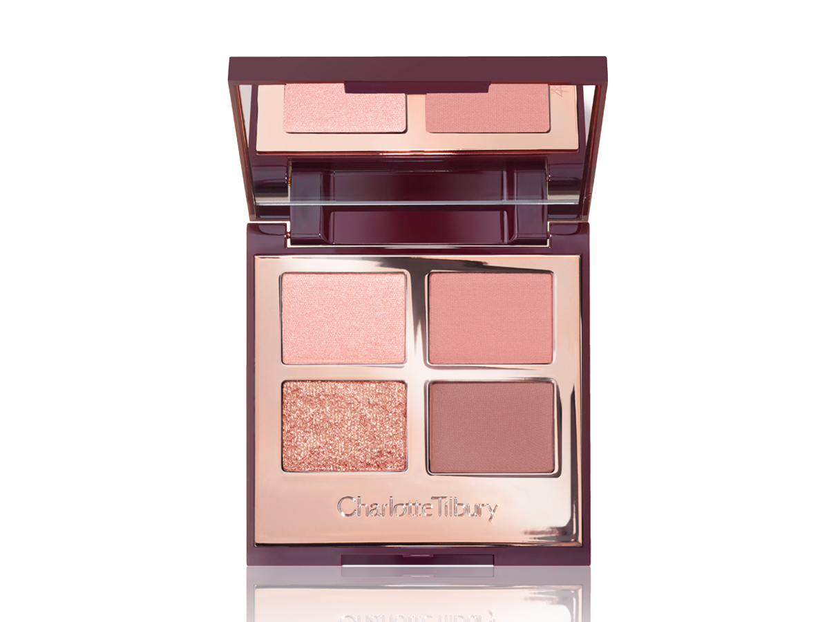 An open, mirrored-lid, quad eyeshadow palette with matte and shimmery eyeshadows in nude-pink, brown, and beige shades. 