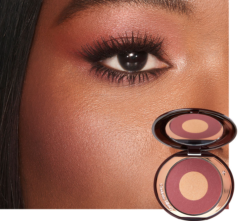 Close-up of a deep-tone model with brown eyes wearing shimmery berry-pink eyeshadow with a berry-rose blush with champagne undertones.