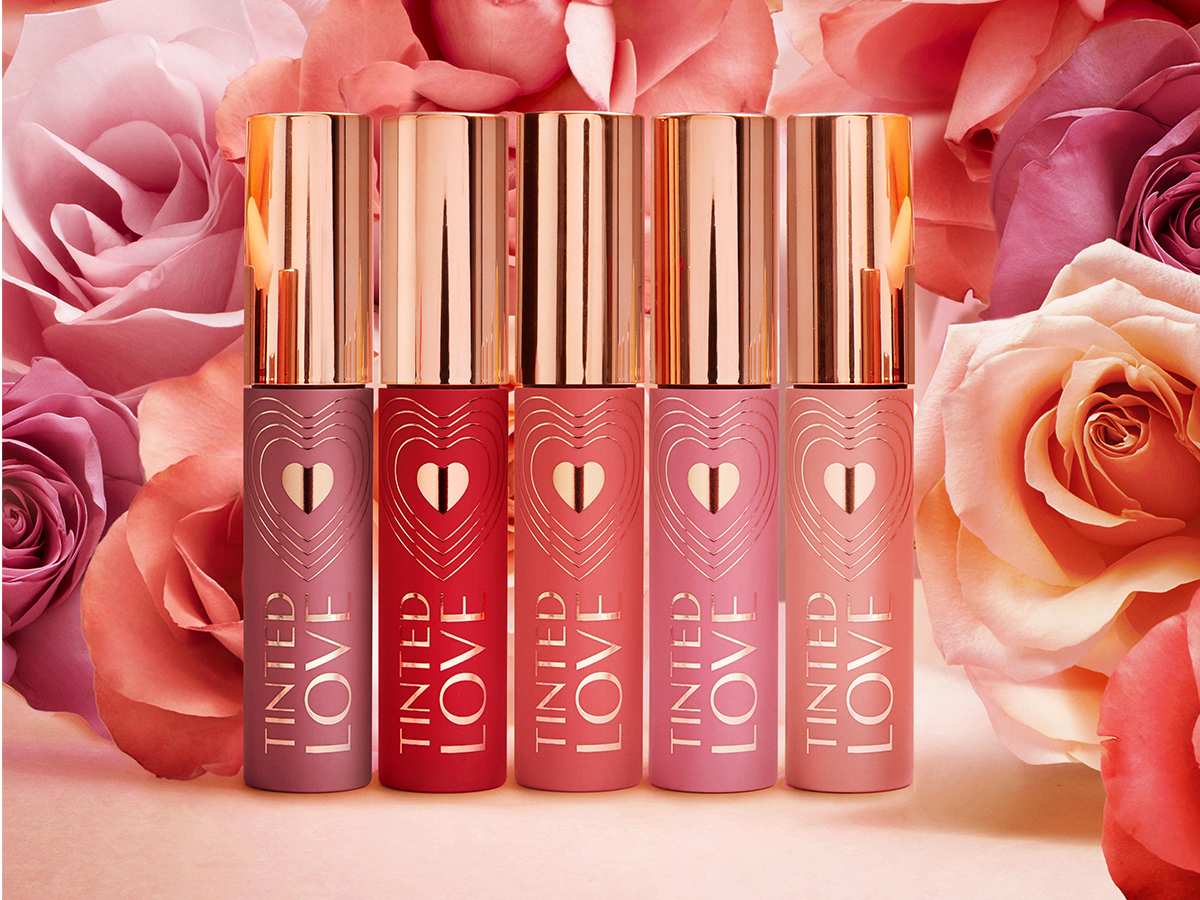 A collection of lip and cheek tints in shades of purple, red, peach, coral, and pink with tubes the colour of the tint inside and gold-coloured lid.