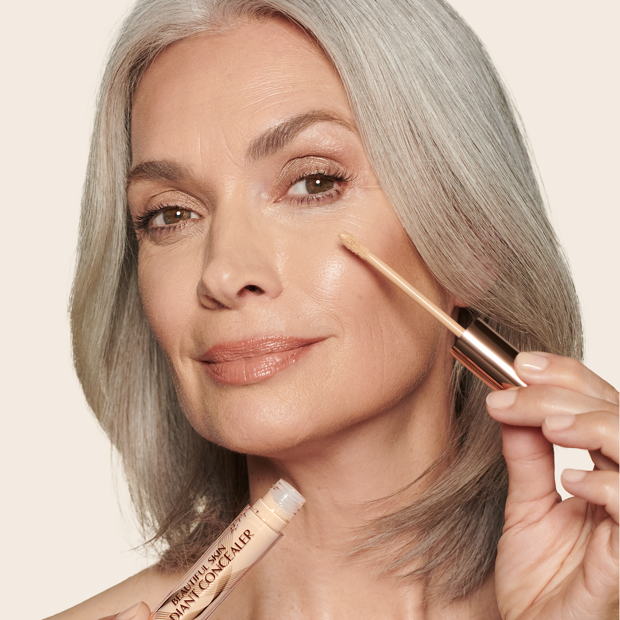 Light-tone model with mature skin and brown eyes wearing a radiant, concealer that brightens, covers blemishes, and makes her skin look fresh along with nude lip gloss and subtle eye makeup.