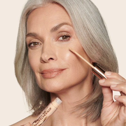 Light-tone model with mature skin and brown eyes wearing a radiant, concealer that brightens, covers blemishes, and makes her skin look fresh along with nude lip gloss and subtle eye makeup.