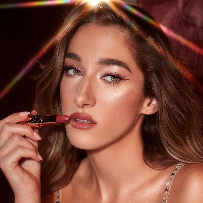 K.I.S.S.I.N.G in Rosy Seduction on fair-tone model Fair-tone brunette model wearing satin finish lipstick in a rose pink shade with full-glam peachy-pink glowy makeup.