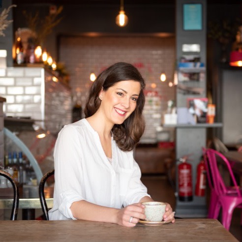 Margareta Serfozo, a nutritionist and health coach, sitting in a cafe while drinking tea.