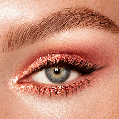 Single-eye close-up of a fair-tone model with blue eyes wearing shimmery rose gold cream eyeshadow.