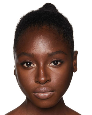 A deep-tone brunette model wearing glowy, nude makeup with bronzed skin. 