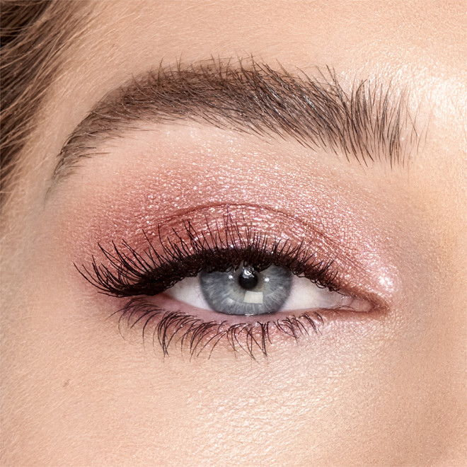 Single-eye close-up of a fair-tone model with blue eyes wearing shimmery rose gold eyeshadow.