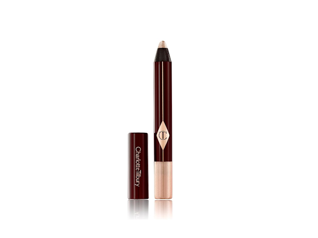 An open, chubby eyeshadow stick in a shimmery champagne shade with its lid next to it. 