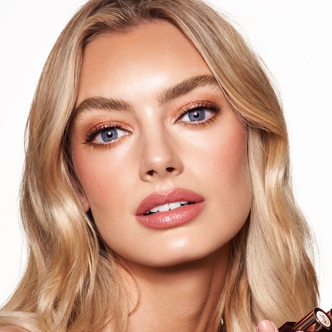 Quick & Easy Instant 5 Minute Golden Glow Look on fair-tone model Fair-tone blonde model with blue eyes wearing shimmery bronze eyeshadow with black eyeliner, nude rose matte lipstick with nude rose blush, and glowy opal-coloured highlighter for a flawless, glowy look.