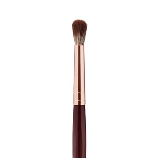 Close-up of an eyeshadow blending brush with soft bristles and a rose-gold and dark crimson handle. 