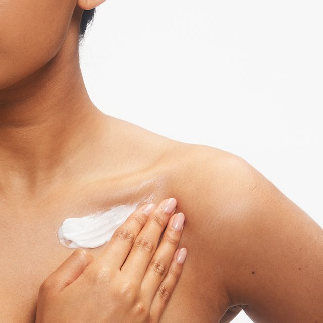 Model applying Charlotte's Magic Body Cream to the shoulders and chest
