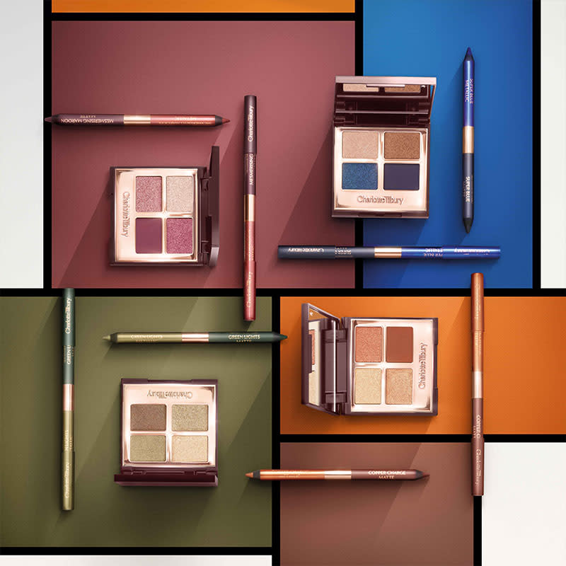 four quad eyeshadow palettes and dual-ended eyeliner pens, all open, in shades of blue, copper, maroon, and green, placed on a complementary background. 