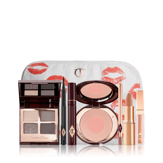 A makeup pouch with an open, mirrored-lid eyeshadow palette in matte and shimmery silver, grey, and beige shades, an open black eyeliner pen, a mascara in a dark-crimson colour scheme, a nude-pink lipstick with a matching lip liner pencil, nude pink lip gloss, and an open two-tone blush in muted rose-gold and pink. 