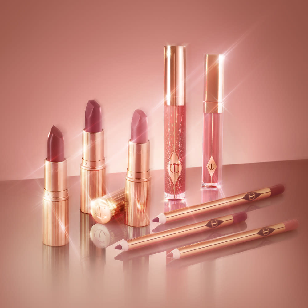 three open lipsticks in light, nude pink, medium pink, and dark berry-pink, lip glosses with and without glitter in nude pink, three, open lip liners in matching shades of pink.