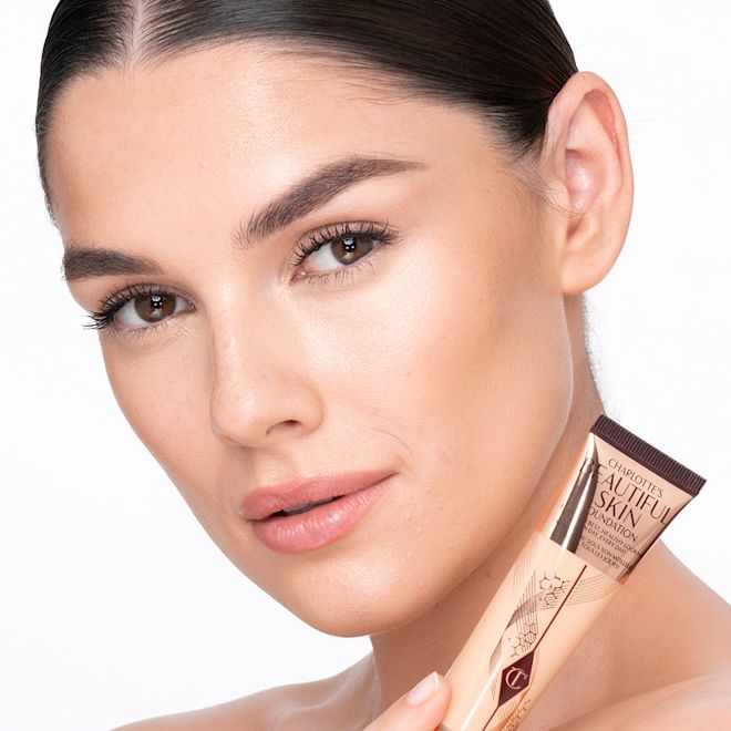 Beautiful Skin Foundation in 4W on medium-light-tone model after application Medium-light-tone brunette model wearing glowy, skin-like foundation with a satin finish with nude lipstick and subtle eye makeup.