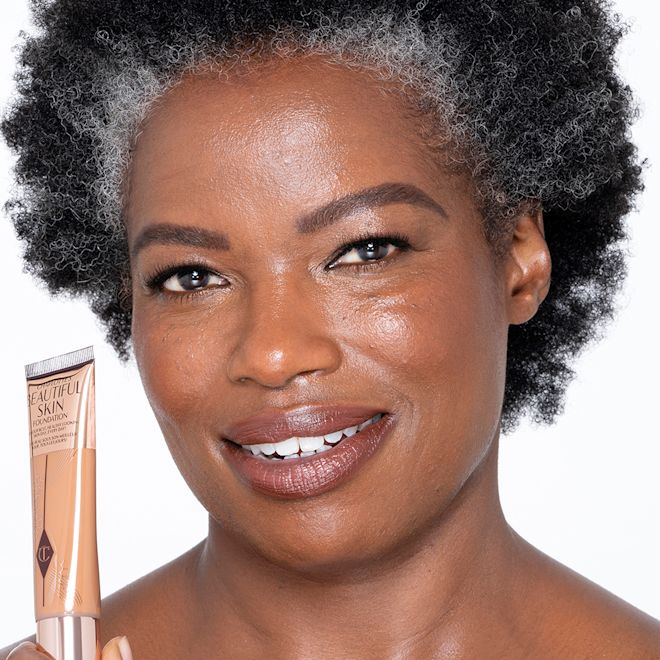 Beautiful Skin Foundation in 14C on deep-tone model Dark-tone brunette model wearing glowy, skin-like foundation with a satin finish with nude lipstick and subtle eye makeup.