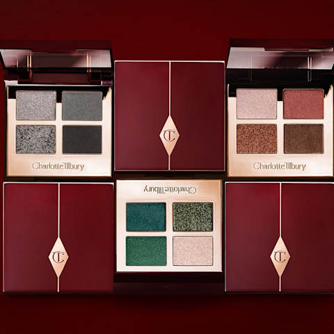 Three open, quad eyeshadow palettes in shades of grey, green, and brown. 