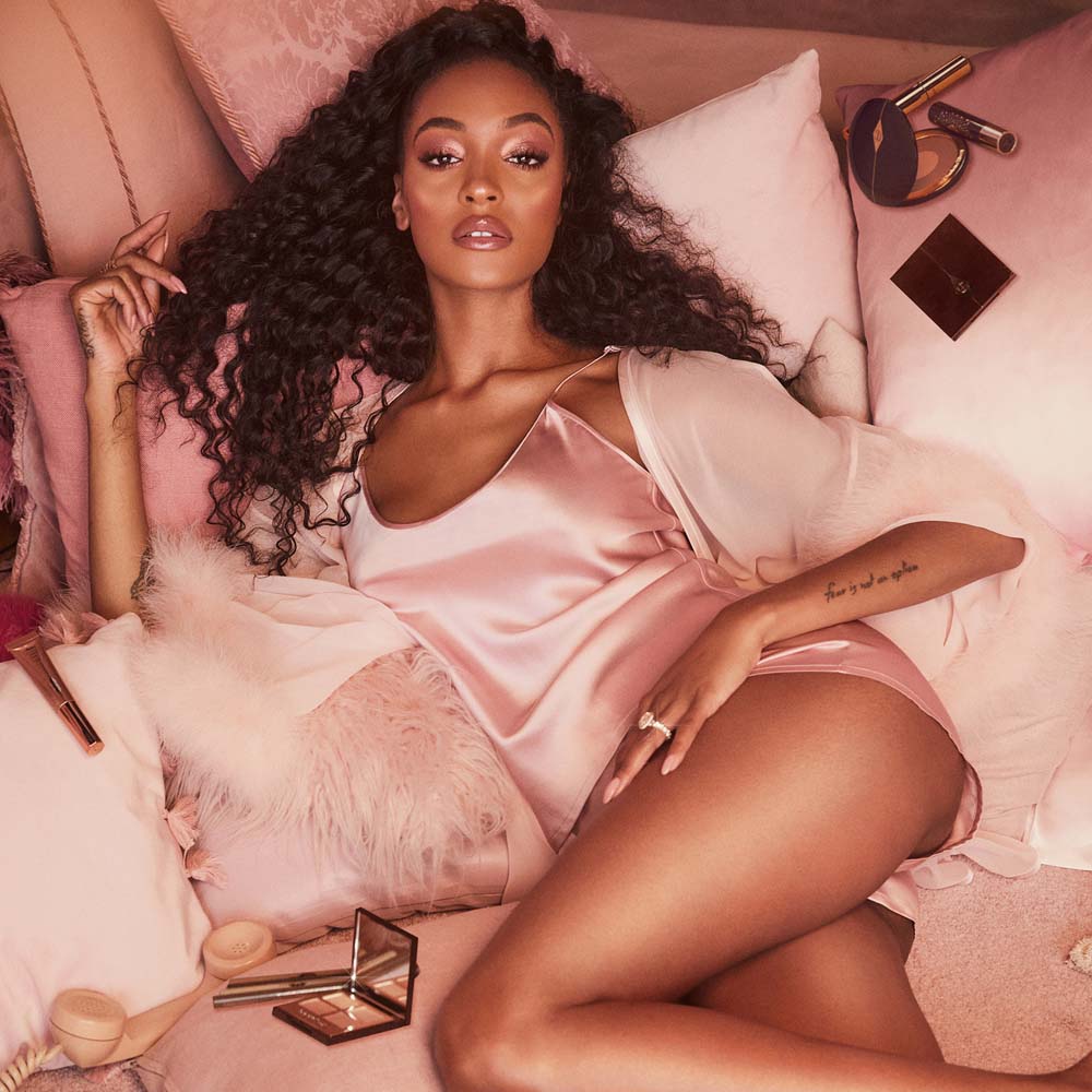 Deep-tone model wearing nude pink, glowy, full-glam makeup, perfect for an evening or night look with a pink-coloured dress.