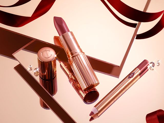 An open rose-pink lip liner pencil and open rose-pink lipstick, both in the iconic, golden, Charlotte Tilbury packaging. 