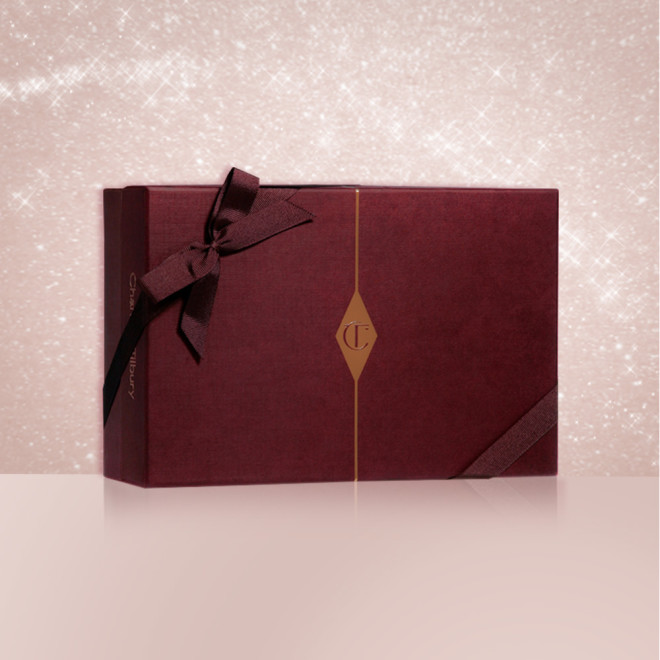 A dark crimson-coloured gift box with a matching bow on it and the CT logo printed on the middle of the box.
