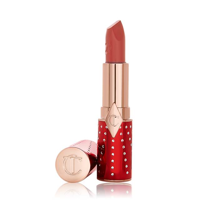 K.I.S.S.I.N.G in Sweet Blossom lid removed An open lipstick in a rusty rose-coloured shade with a satin-finish in a red and gold-coloured tube.