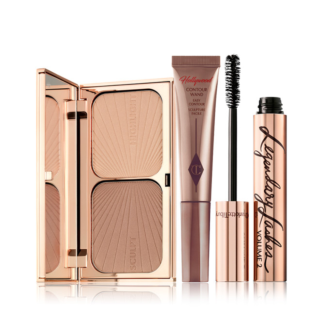 An open duo contour palette for light to medium skin tone, a medium-brown liquid contour wand, and a black mascara in golden packaging with its applicator next to it. 