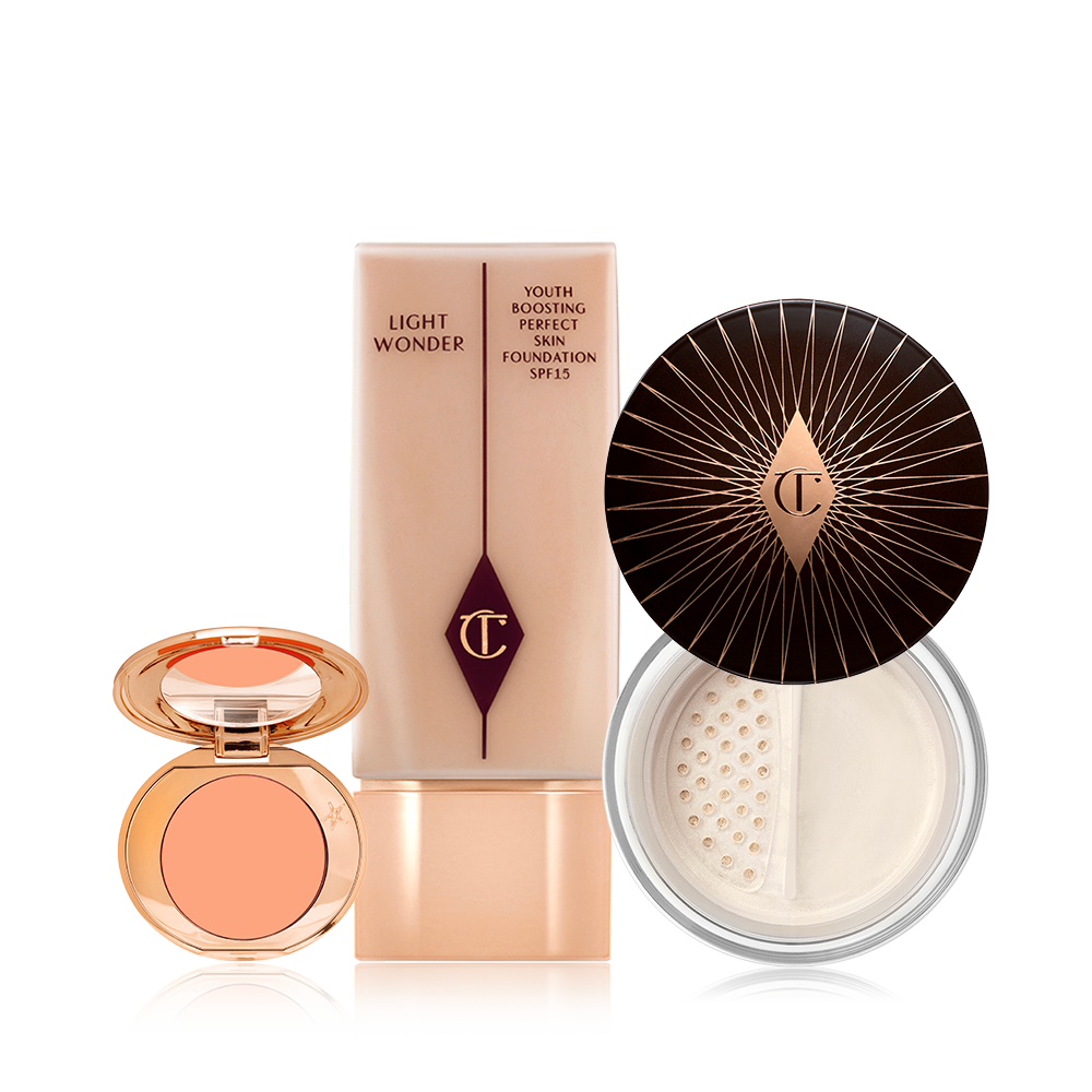 An open colour correcting compact with a mirrored-lid, foundation in a clear bottle with  arose-gold-coloured lid, and loose powder with its lid removed.