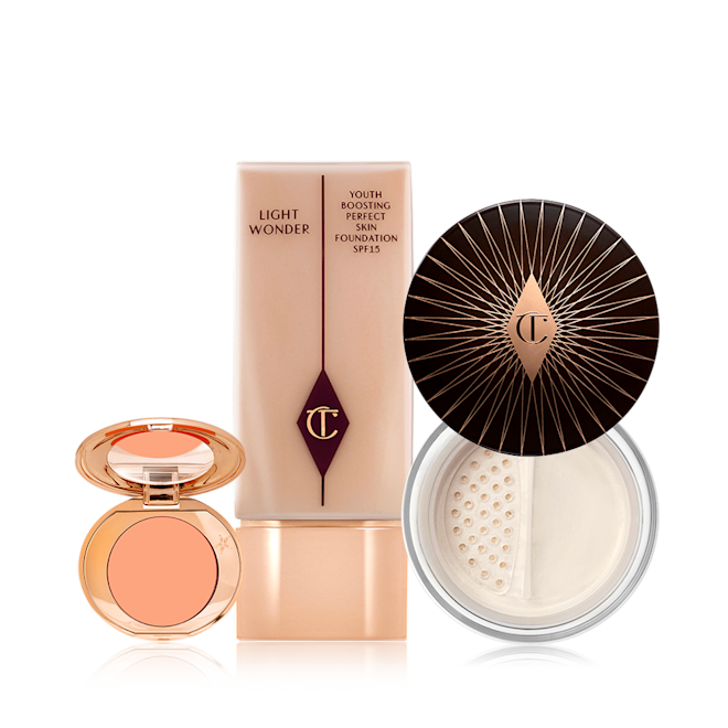 Fresh Glowing Complexion Kit displayed An open colour correcting compact with a mirrored-lid, foundation in a clear bottle with arose-gold-coloured lid, and loose powder with its lid removed.