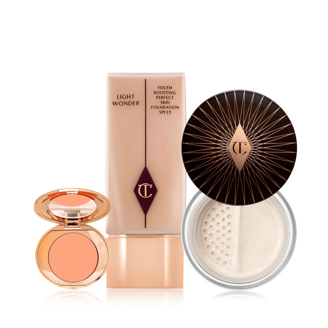 An open colour correcting compact with a mirrored-lid, foundation in a clear bottle with  arose-gold-coloured lid, and loose powder with its lid removed.