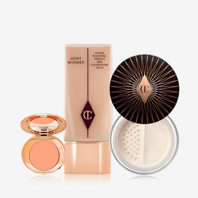 Fresh Glowing Complexion Kit displayed An open colour correcting compact with a mirrored-lid, foundation in a clear bottle with arose-gold-coloured lid, and loose powder with its lid removed.
