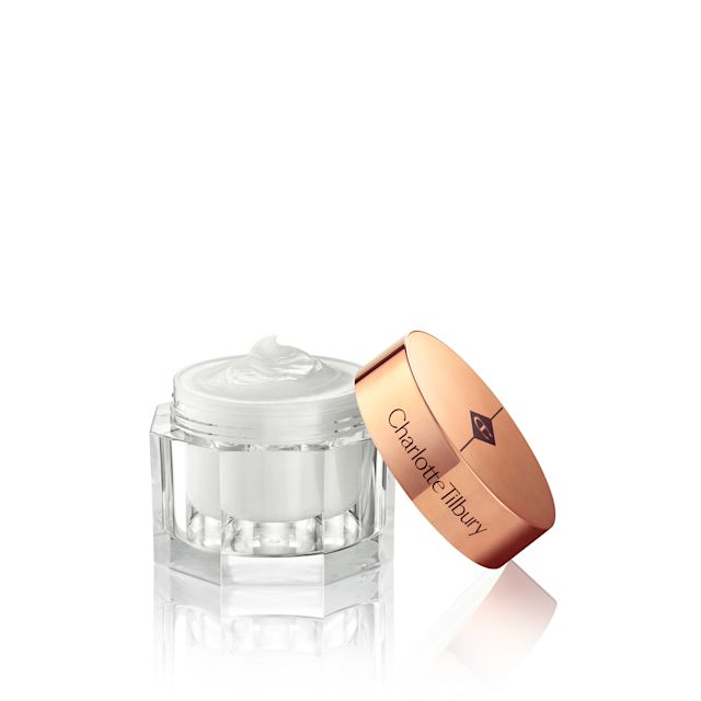 Thick and luscious pearly-white moisturiser in an open glass jar with its gold-coloured lid placed behind it. 