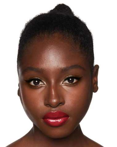 A deep-tone model with brown eyes wearing shimmery bronze eye makeup with muted pink blush and glossy scarlet-red lips