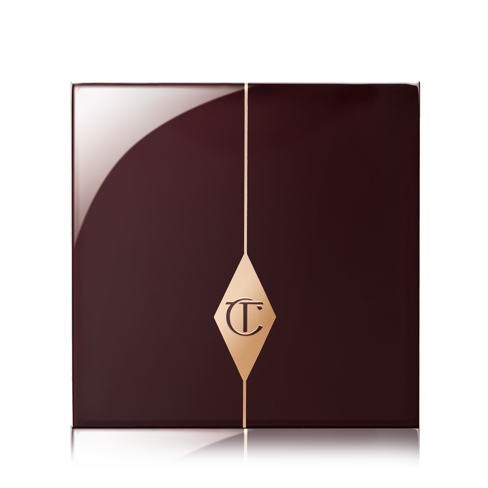 A closed eyeshadow palette with dark crimson packaging with the CT logo printed in the middle in a gold-colour.