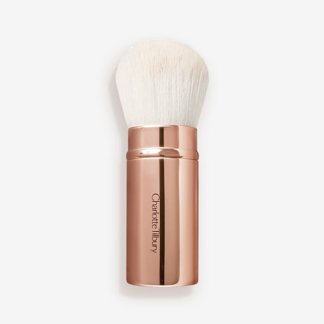The Air Brush Bronzing Brush opened A face blending brush with white bristles in rose gold packaging.